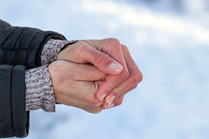 A person rubbing their hands together for warmth.