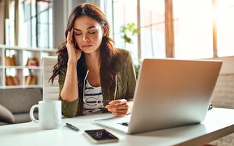 A woman at her desk, looking tired. A woman at her desk, looking tired.