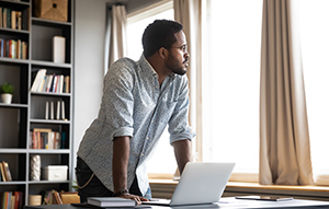 A man gets up from his desk and glances out the window.
