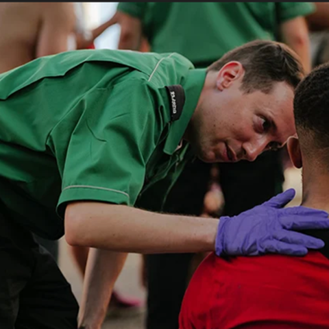 A volunteer putting their hand on the shoulder of a man sitting down.