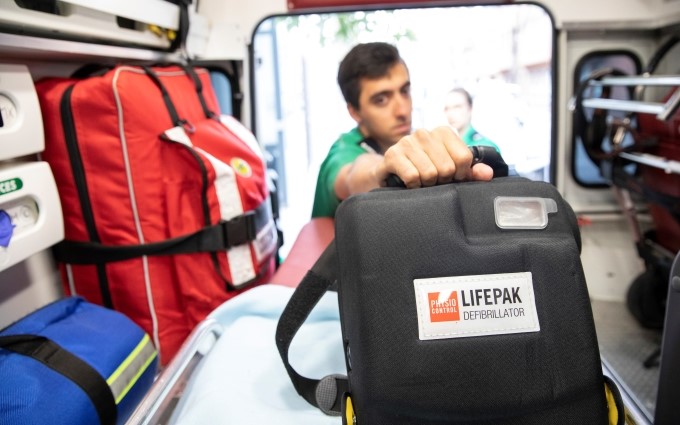 A volunteer holding up a defibrillator.