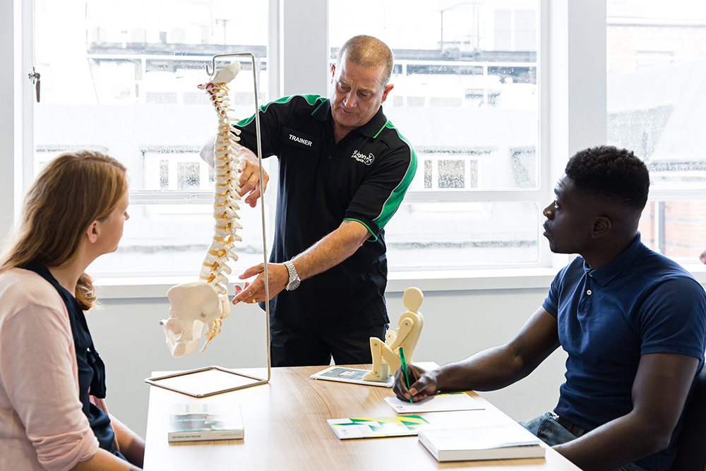 Students learn about spinal anatomy with support from a St John Ambulance trainer