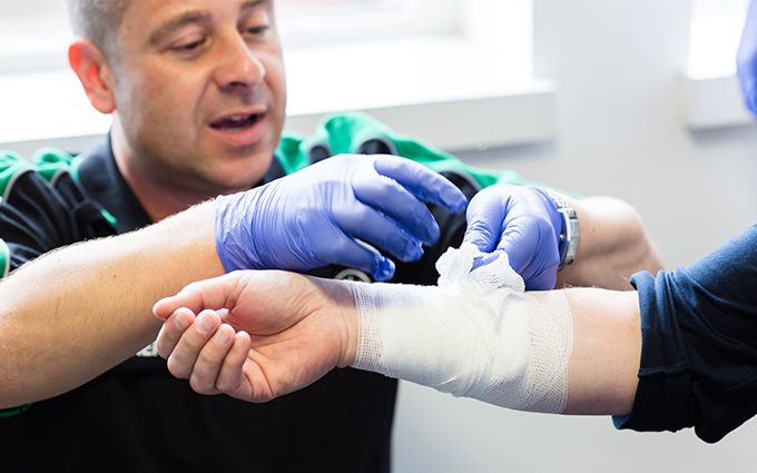 A first aid trainer demonstrating how to put on a bandage.